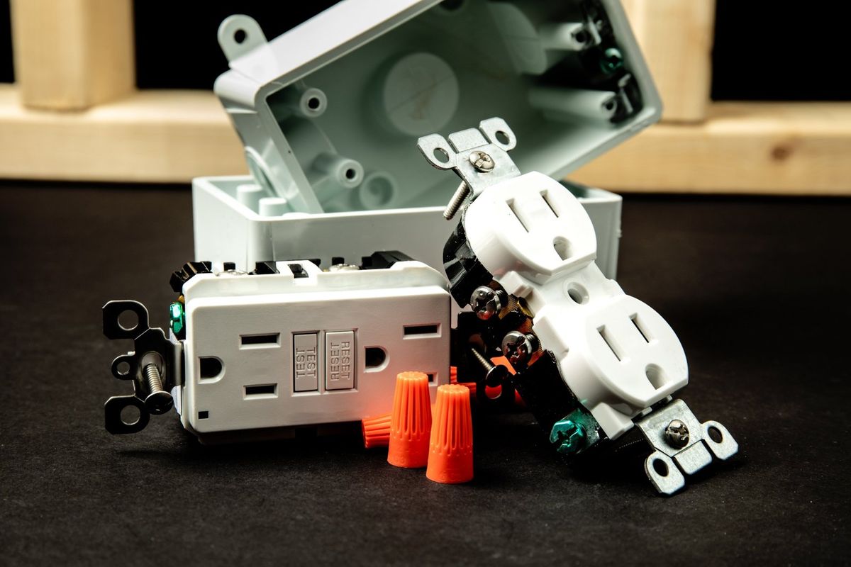 GFCI receptacle with test and reset buttons next to a standard outlet, wire nuts and an electrical box