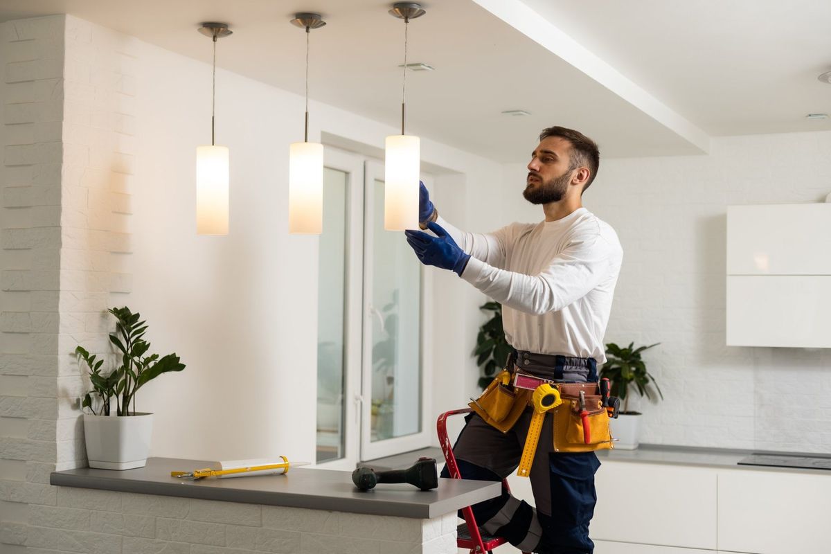 Electrician installing pendant light fixtures over a kitchen counter